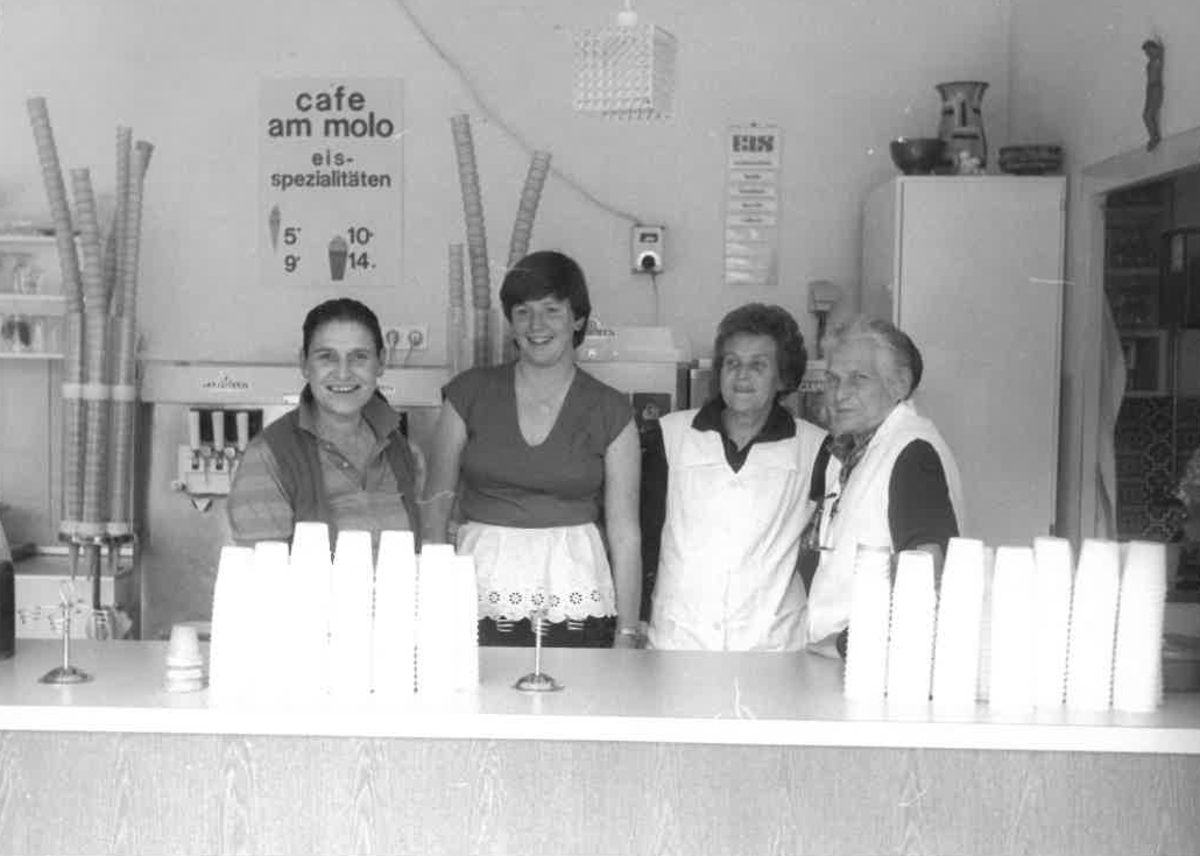 Das Team hinter der Theke des Café am Molo, darüber das Schild „cafe am molo · eis-spezialitäten“