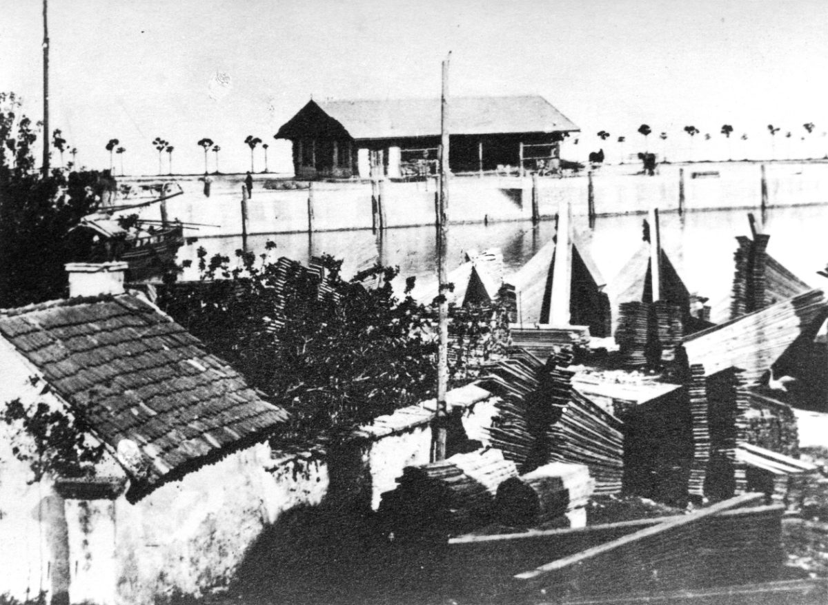 Das Bregenzer Seeufer vor der Promenade: gestapeltes Holz, Boote am Wasser und eine hölzerne Halle